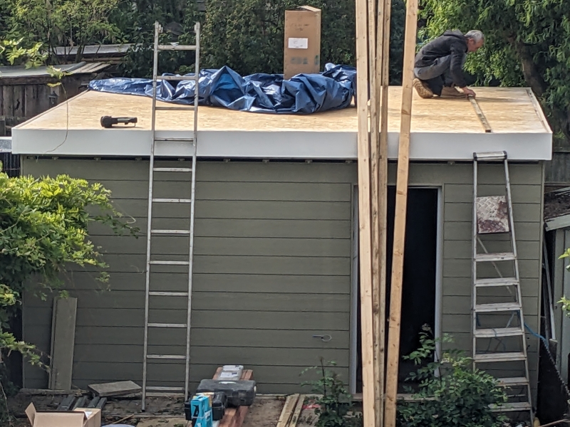 Exterior view showing roof material being laid.